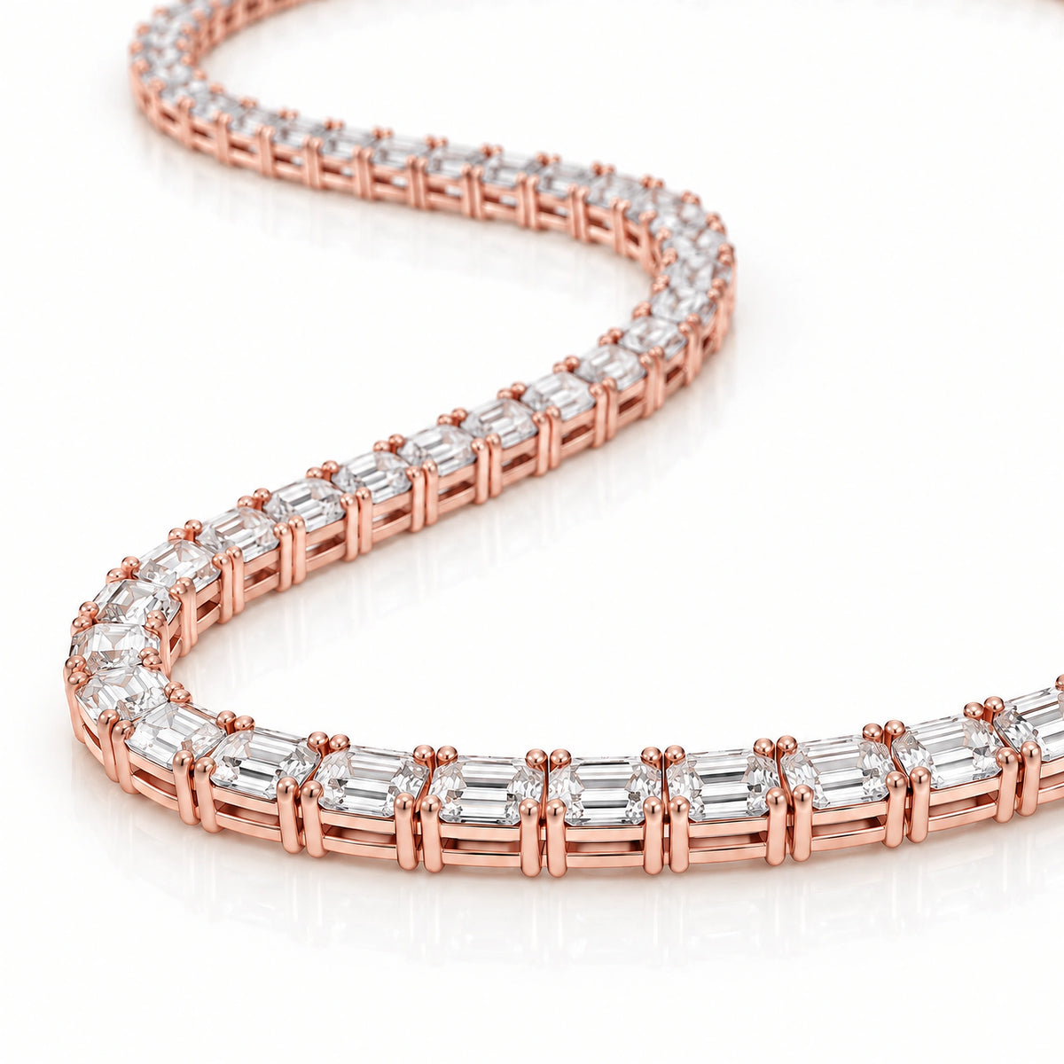 A close-up of a tennis necklace featuring baguette-cut clear stones set in rose gold, arranged in a curved S-shape on a clean white background.